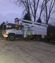 Tree service bucket truck and crew member on a job site
